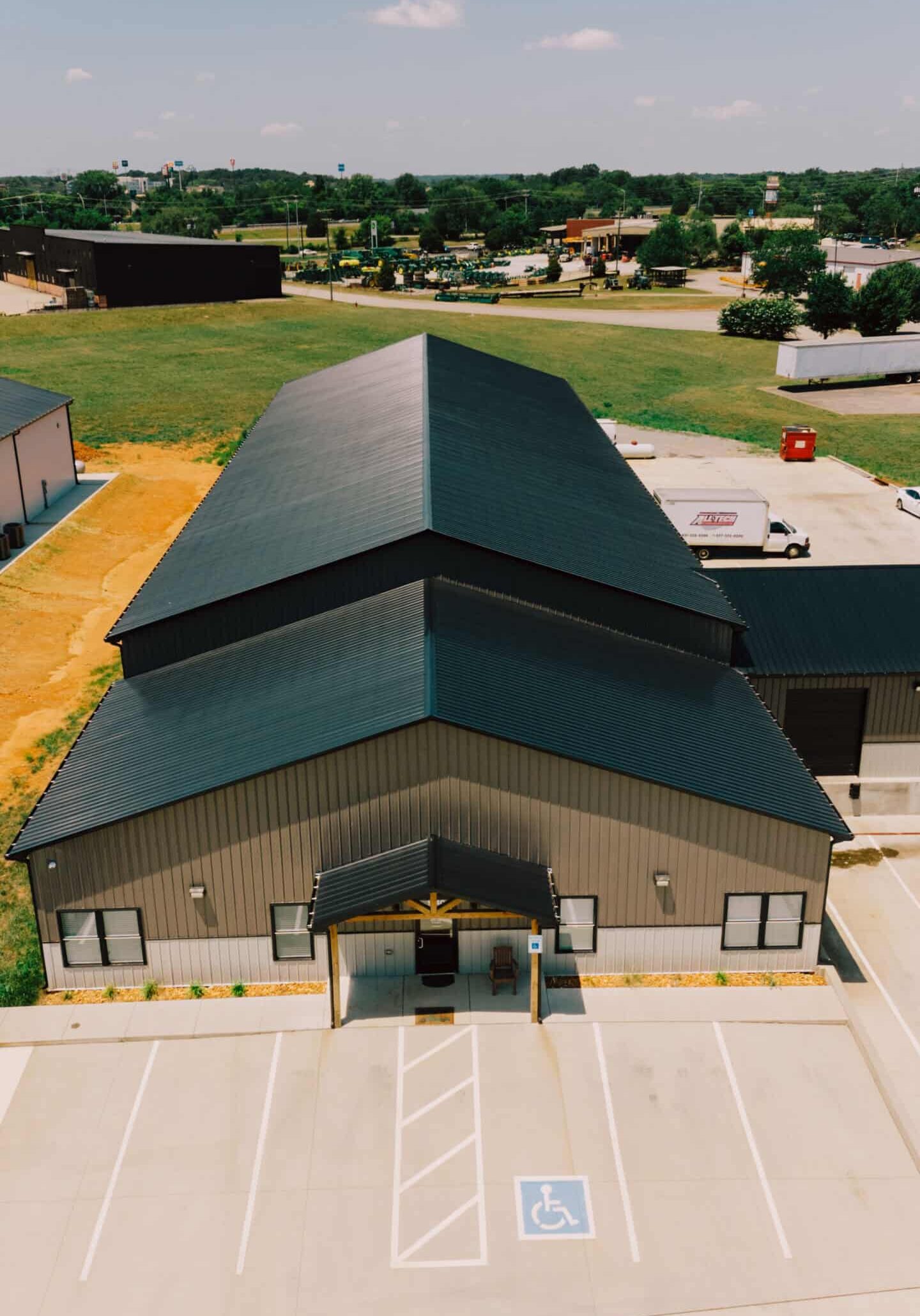 Aerial view of a sleek, modern metal building featuring durable roofing and an accessible parking space with a wheelchair symbol, showcasing quality construction by WW Buildings.